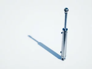 Polished steel hydraulic cylinder with chrome piston rod partially extended on white surface, casting geometric shadow
